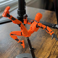 Orange 3D-printad robotfigur i pose